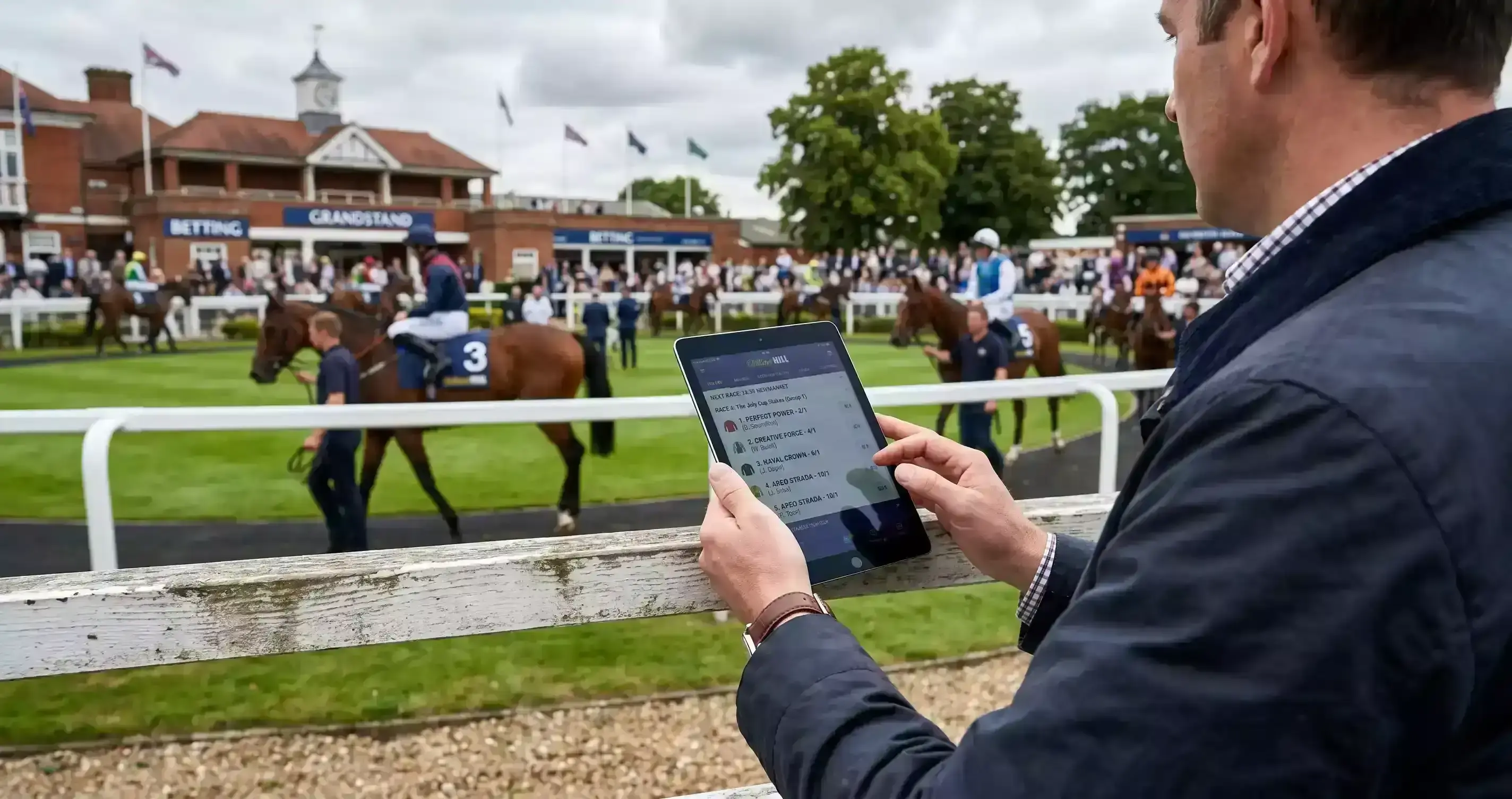 Punter reviewing horse racing selections on a tablet at a racecourse with the track visible in the background